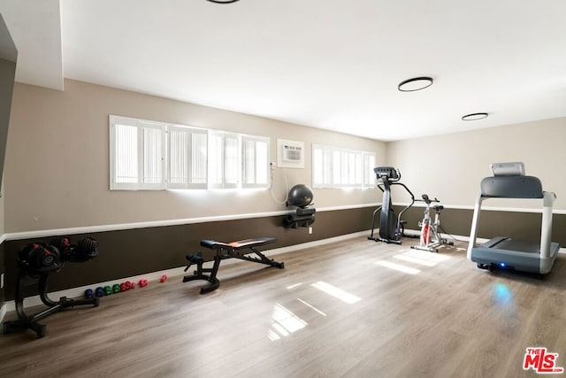 workout room with wood-type flooring and a wall mounted air conditioner