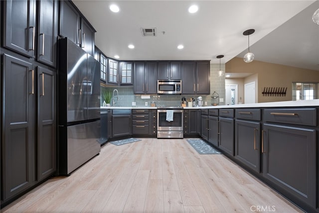 kitchen with lofted ceiling, decorative backsplash, hanging light fixtures, light hardwood / wood-style floors, and stainless steel appliances