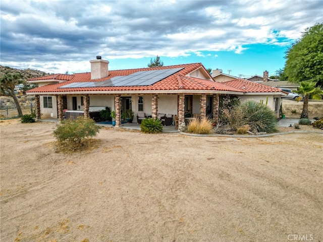 view of front of house with a porch, solar panels, and a patio