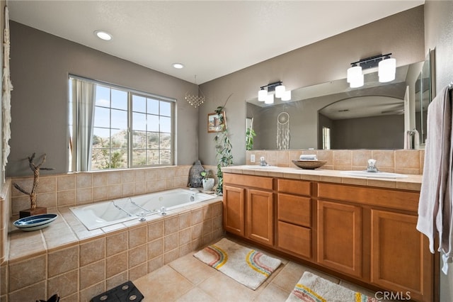 bathroom featuring vanity, a relaxing tiled tub, and tile patterned floors