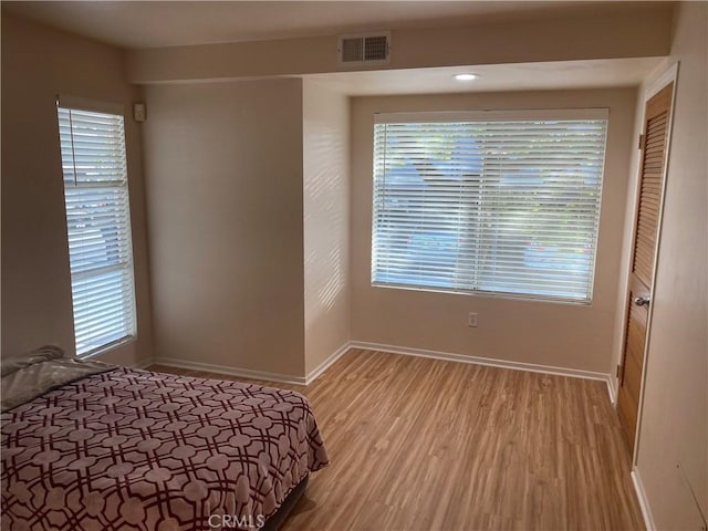 bedroom featuring multiple windows and light hardwood / wood-style floors