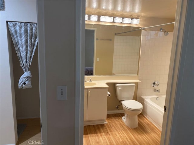 full bathroom with hardwood / wood-style flooring, tiled shower / bath, vanity, and toilet