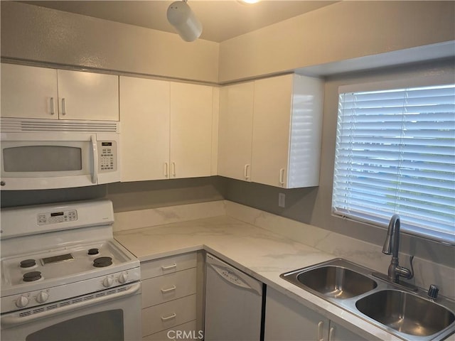 kitchen featuring light stone counters, white appliances, sink, and white cabinets