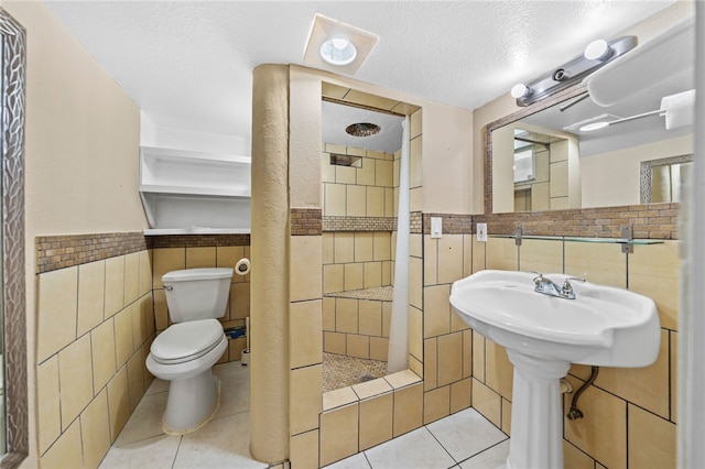 bathroom featuring a textured ceiling, tile patterned flooring, toilet, and tile walls