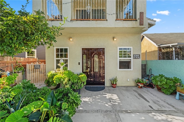 view of exterior entry featuring a balcony and a patio