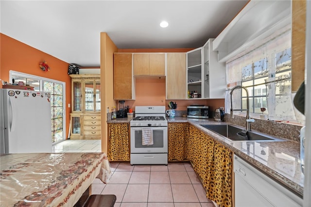 kitchen featuring a wealth of natural light, light stone countertops, sink, white appliances, and light tile patterned flooring