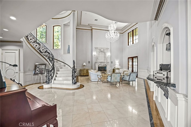 foyer with a premium fireplace, crown molding, and a notable chandelier