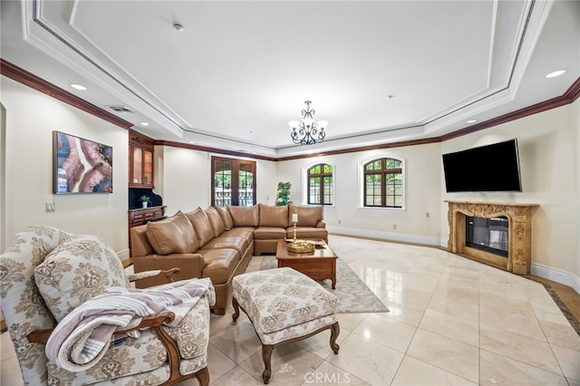 living room with a high end fireplace, crown molding, a tray ceiling, and plenty of natural light