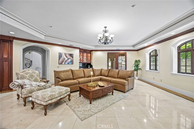 living room featuring ornamental molding, a tray ceiling, and an inviting chandelier