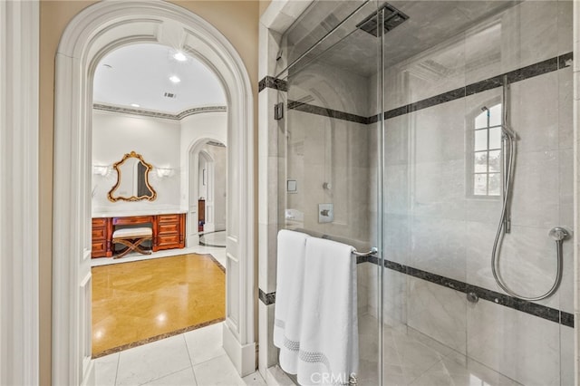 bathroom with a shower with door, ornamental molding, and tile patterned flooring