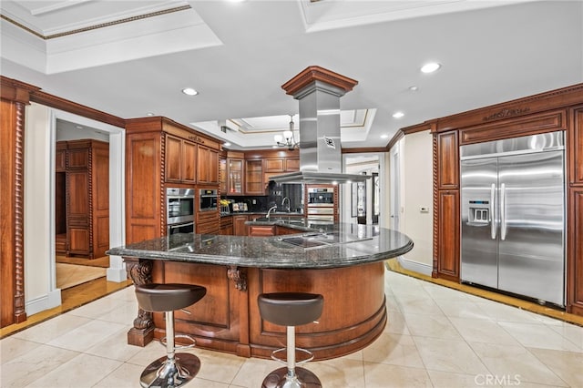 kitchen with a large island with sink, ornamental molding, a kitchen bar, appliances with stainless steel finishes, and tasteful backsplash