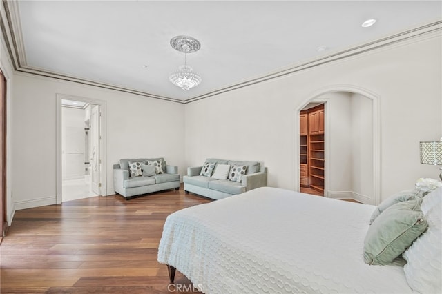 bedroom with hardwood / wood-style floors, crown molding, a walk in closet, and a closet