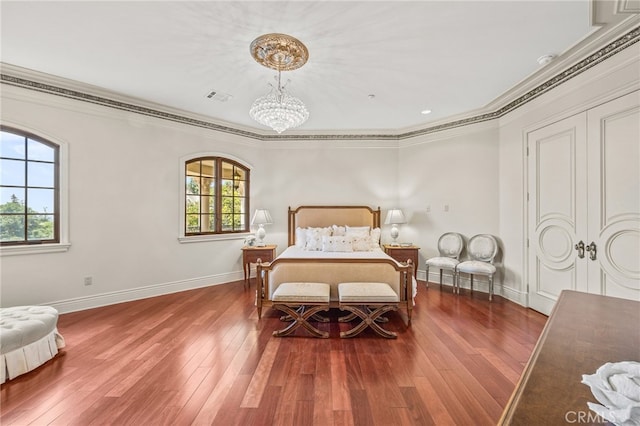 bedroom with an inviting chandelier, crown molding, and dark hardwood / wood-style flooring