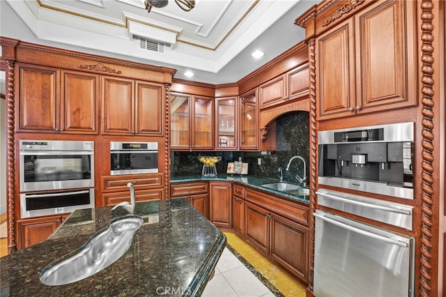 kitchen with tasteful backsplash, sink, a raised ceiling, dark stone counters, and crown molding