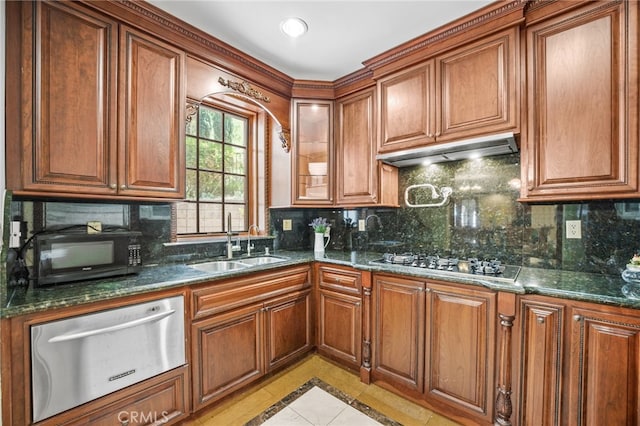 kitchen featuring backsplash, dark stone countertops, sink, light tile patterned floors, and stainless steel gas stovetop