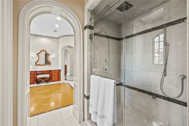 bathroom featuring a shower with door, tile patterned floors, and ornamental molding