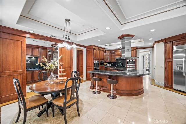 tiled dining space with ornate columns, ornamental molding, and a tray ceiling