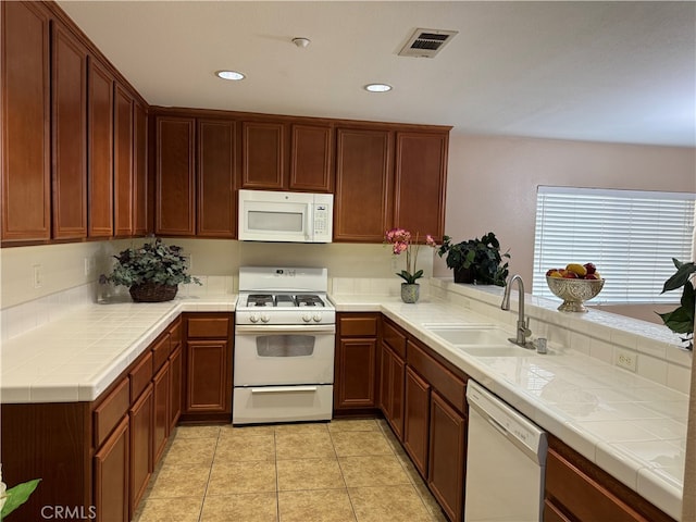 kitchen featuring kitchen peninsula, tile countertops, light tile patterned flooring, sink, and white appliances