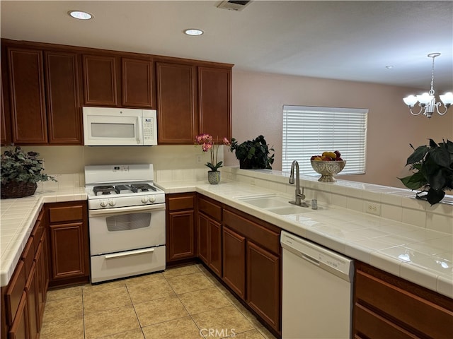 kitchen featuring tile countertops, sink, an inviting chandelier, and white appliances