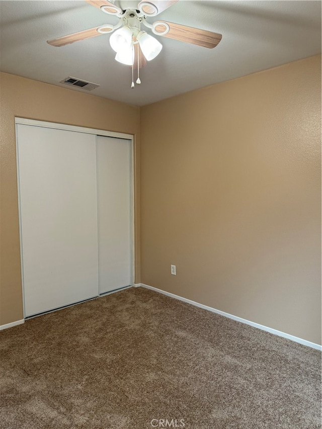 unfurnished bedroom featuring carpet, a closet, and ceiling fan