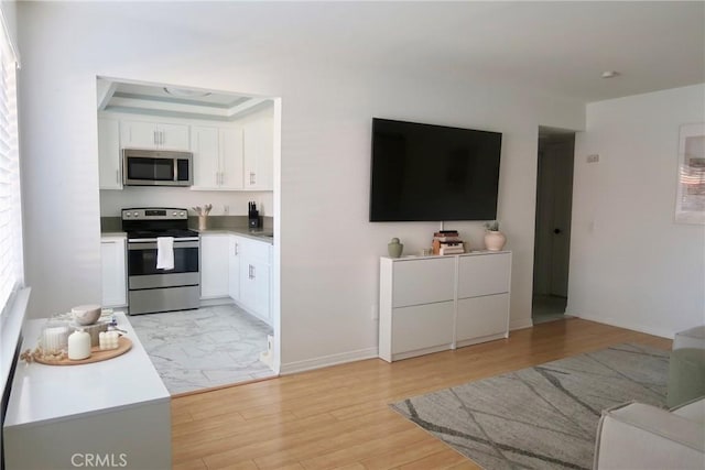 kitchen with light hardwood / wood-style flooring, white cabinets, and stainless steel appliances