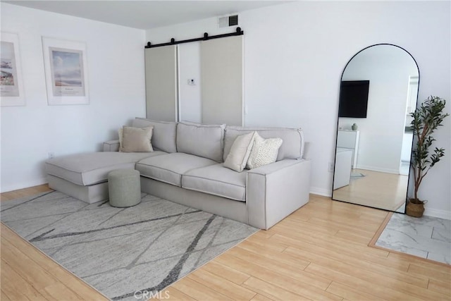 living room featuring a barn door and light hardwood / wood-style flooring