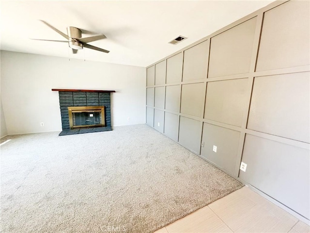 unfurnished living room with a fireplace, light colored carpet, and ceiling fan