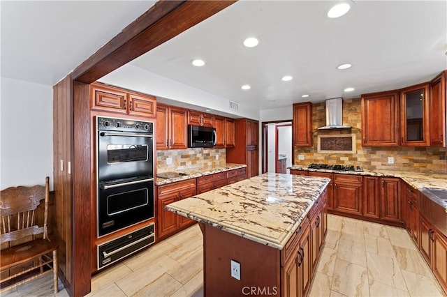 kitchen with a center island, light stone countertops, wall chimney range hood, and stainless steel appliances