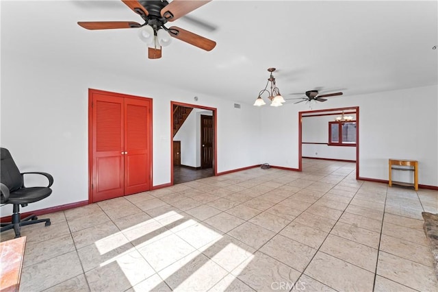 tiled empty room with ceiling fan with notable chandelier