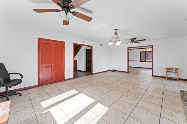 tiled spare room featuring ceiling fan with notable chandelier