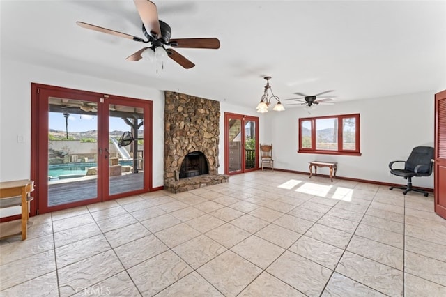 unfurnished living room with a fireplace, ceiling fan with notable chandelier, and light tile patterned flooring