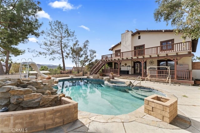 view of pool with an in ground hot tub, a diving board, a patio area, and a water slide