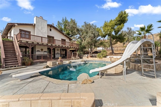 view of pool featuring a deck, a diving board, a patio area, and a water slide