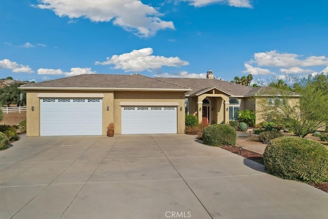 ranch-style house featuring a garage, a tile roof, driveway, and stucco siding