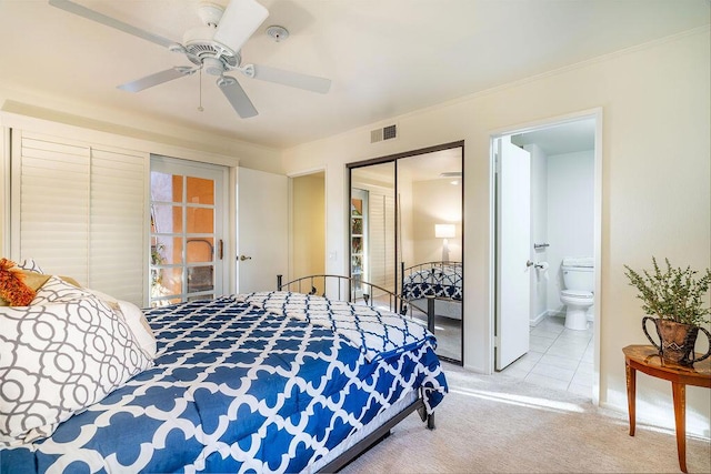 carpeted bedroom with a closet, ensuite bath, and ceiling fan