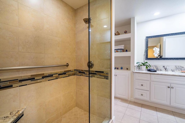 bathroom with tiled shower, vanity, and tile patterned flooring