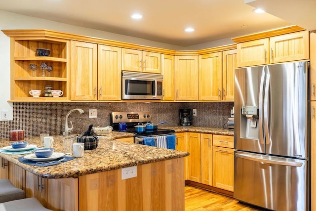 kitchen featuring light stone countertops, appliances with stainless steel finishes, tasteful backsplash, light brown cabinets, and light hardwood / wood-style flooring