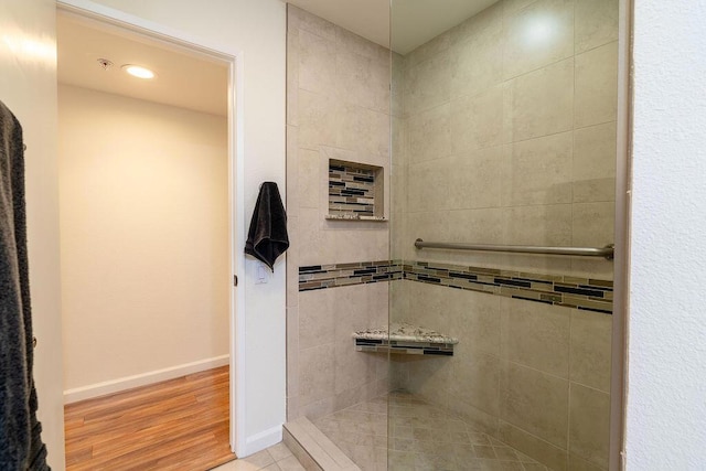 bathroom with tiled shower and hardwood / wood-style flooring