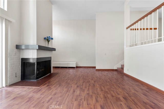 unfurnished living room featuring dark wood-type flooring, a high ceiling, and a multi sided fireplace