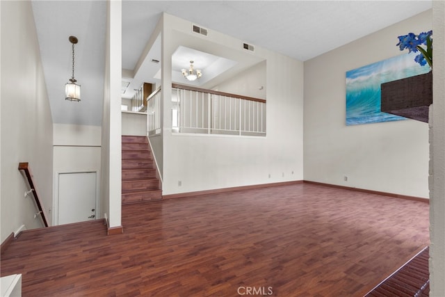 unfurnished living room with a notable chandelier and dark hardwood / wood-style flooring