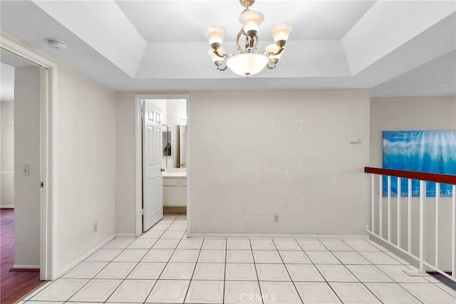 empty room with a tray ceiling and a chandelier