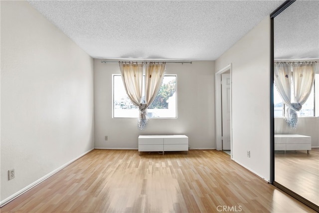 unfurnished room with light hardwood / wood-style flooring and a textured ceiling