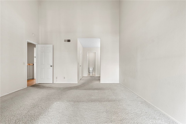 carpeted empty room featuring a high ceiling