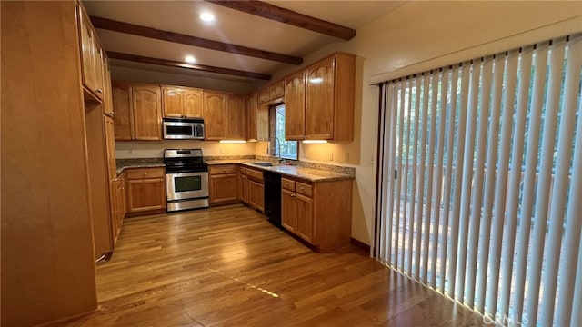 kitchen with light hardwood / wood-style flooring, beam ceiling, stainless steel appliances, and sink