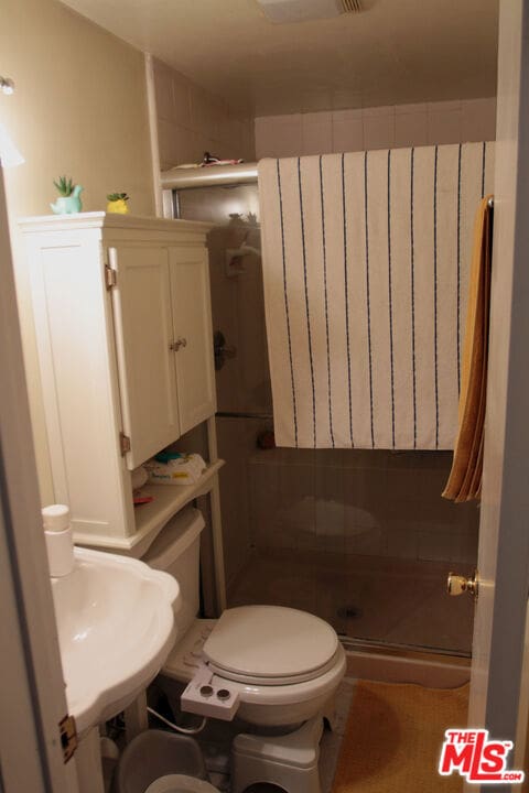 bathroom featuring toilet and a shower with shower door