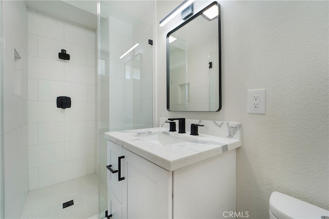 bathroom featuring toilet, vanity, and tiled shower