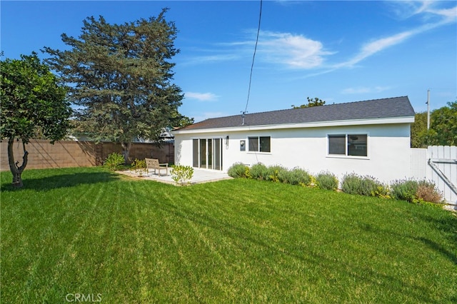 back of house with a patio and a lawn