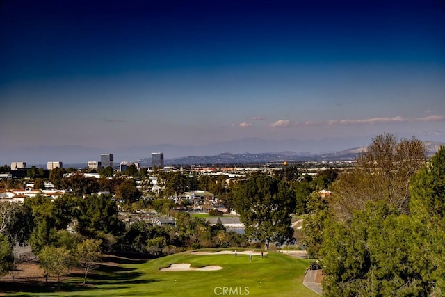 view of community featuring a view of city, a mountain view, golf course view, and a yard