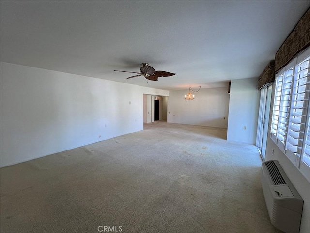 empty room featuring light carpet, a wall mounted AC, and ceiling fan with notable chandelier