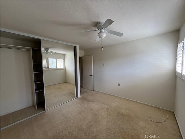 unfurnished bedroom featuring light carpet, a closet, and a ceiling fan